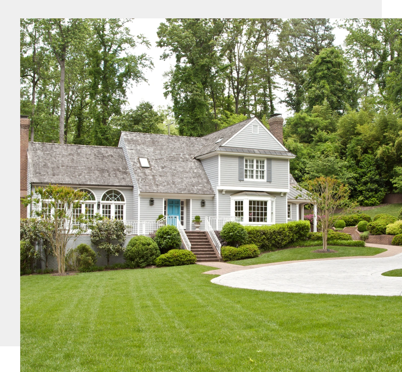 Gray house with blue door and manicured lawn.